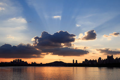 Silhouette buildings by city against sky during sunset