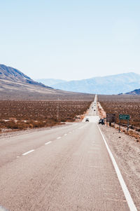 Road leading towards mountain against sky