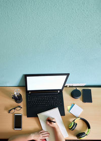 Unrecognizable woman writes on her notebook on a desk in her home