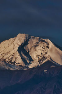 Close-up of rocky mountain against blue sky