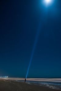 Person holding torch on beach against clear sky at night