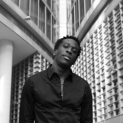 Low angle view of young man looking away against building