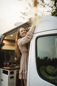 Smiling woman looking away while standing in motor home