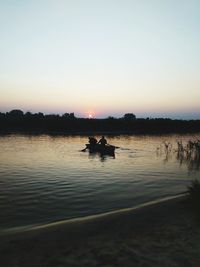 Silhouette person in lake against clear sky during sunset