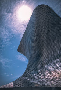 Low angle view of modern building against cloudy sky