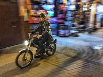 Man riding motorcycle on street at night