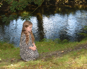 Full length of girl sitting by lake
