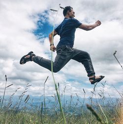 Full length of man jumping on field against sky