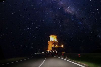 Illuminated road against sky at night