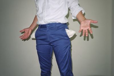 Midsection of man with empty pockets standing against wall