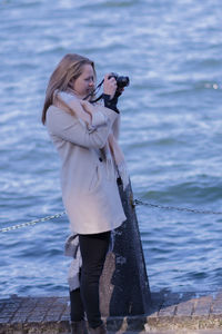Full length of woman photographing sea