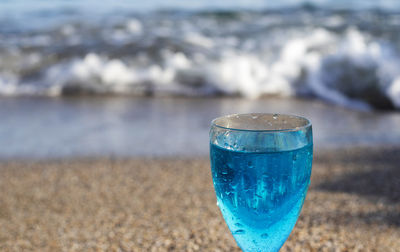 Blue lagoon cocktail on seashore big rock sands shells on sands background summer vacation mockup