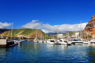 Boats moored on sea against blue sky