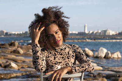 Portrait of young woman at beach against sky