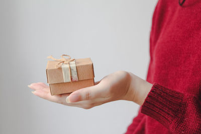 Cropped hand of woman holding gift against white background