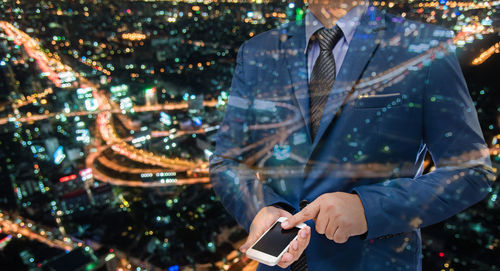 Digital composite image of businessman using mobile phone with cityscape