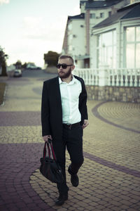 Full length of young man standing on sidewalk in city