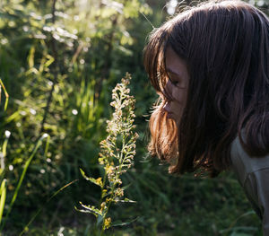 Portrait of a teenager girl blowing at flower in the forest at sunset
