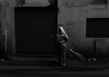 Full length of man standing on footpath against wall