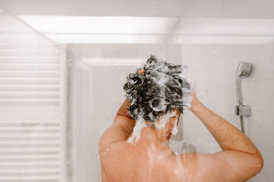 Midsection of man taking a shower in bathroom at home