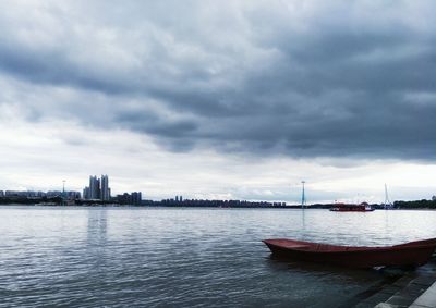 Boats moored in sea against sky in city