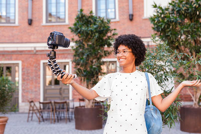 Portrait of a smiling young woman standing against built structure