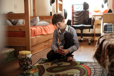 Boy teen plays with designer on the floor in real children's room