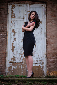 Portrait of smiling woman standing against brick wall