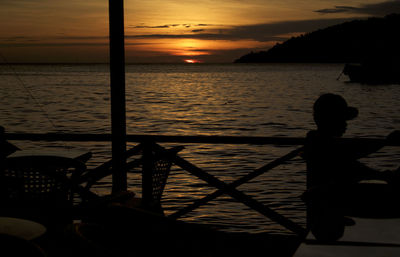 Silhouette woman by sea against sky during sunset