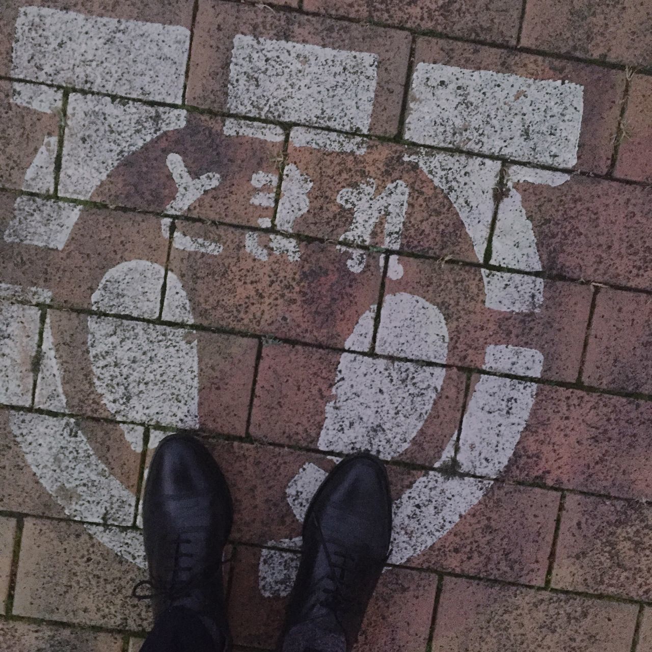 low section, shoe, person, high angle view, standing, personal perspective, paving stone, street, cobblestone, footwear, human foot, directly above, lifestyles, unrecognizable person, tiled floor, sidewalk, men