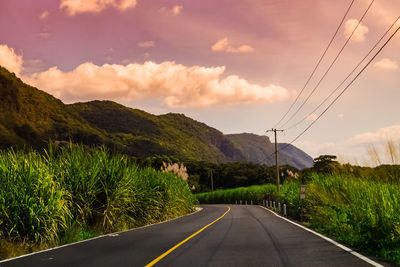 Road leading towards mountains against sky