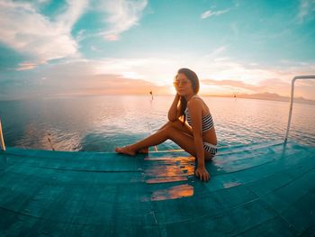 Portrait of young woman in bikini sitting at beach