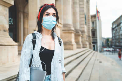 Young woman standing against buildings in city