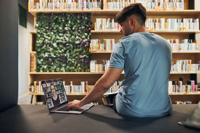 Student learning in university library. young man having video class on laptop. back to school