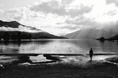 Man standing by lake against sky