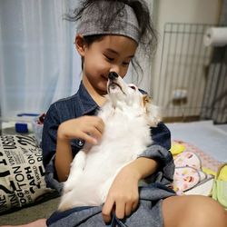 Cute girl playing with dog at home