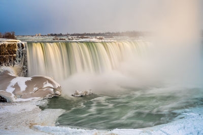 Scenic view of waterfall against sky