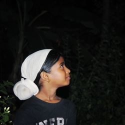 Girl looking away while standing outdoors at night