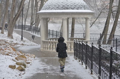 Rear view of man walking in snow during winter