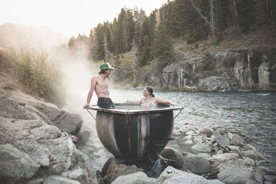 Happy couple in bathtub by river in forest