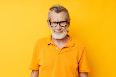 Young man wearing sunglasses while standing against yellow background