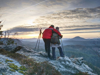 Two wildlife photographers at tripod with set shinning camera enjoy autumn morning in wildnature