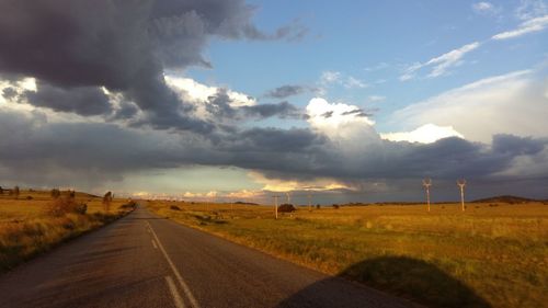 Country road against cloudy sky