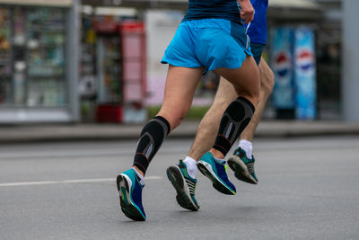Two male athletes runnnig marathon side by side in streets city
