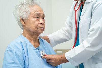 Doctor with stethoscope checking senior or elderly old lady woman patient while  