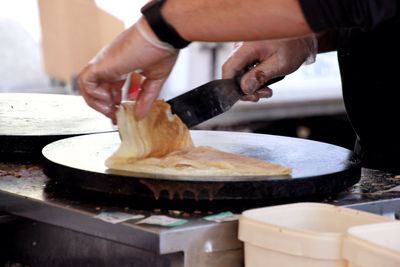 Cropped image of man preparing thosai on stove