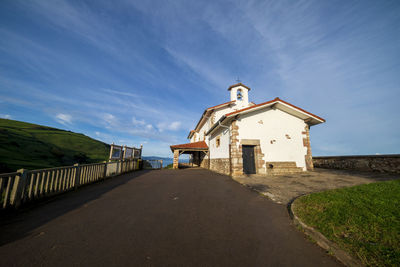 Road by building against blue sky