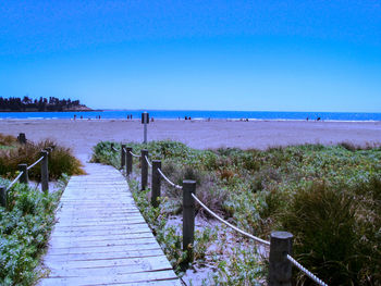 Pier over sea against clear blue sky