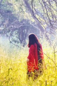 Woman standing on field against trees