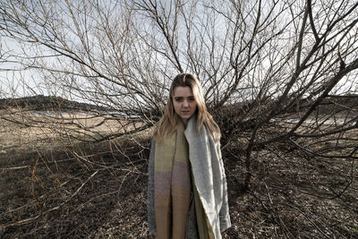 Portrait of woman standing on bare tree